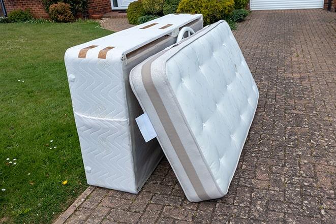 mattress being lifted into a garbage truck